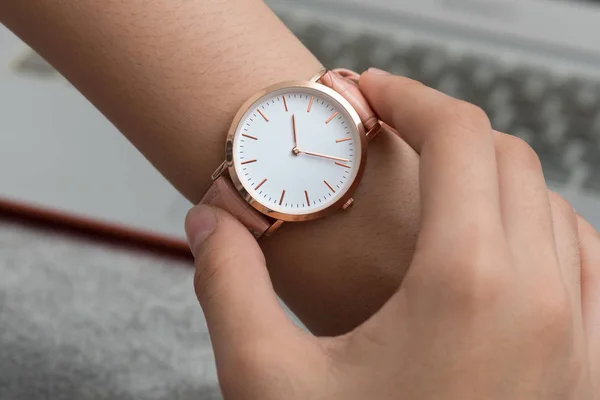 Mano de niña con reloj de pulsera en frente de escritorio con ordenador portátil comput — Foto de Stock