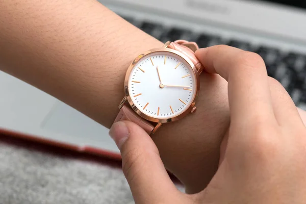 Wrist watch on girl's hand in front of a notebook computer — Stock Photo, Image