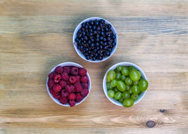 Composição de pratos com framboesas, uvas, groselhas — Fotografia de Stock