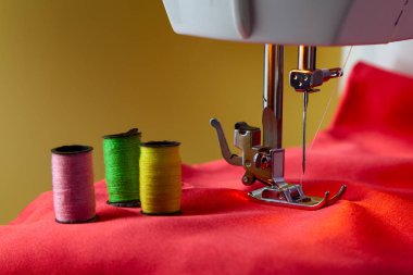Biriktiricileri iplik ve üzerinde kırmızı bir kumaş dikiş makinesi