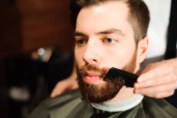 Master cuts hair and beard of men in the barbershop