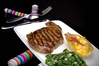 Restoran bifteği, doldurulmuş patates ve kremalı ıspanak. 