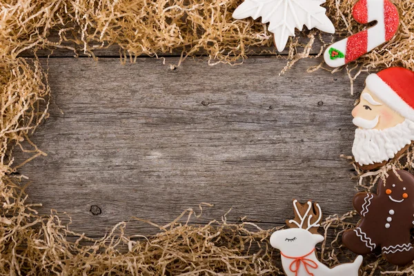 Vánoční rám z borových větví. Dekorace z malovaných zázvorový perník. Perníkový panáček, vánoční cukrové třtiny a sněhulák. Umístěte pod textem. Kopírovat prostor. — Stock fotografie