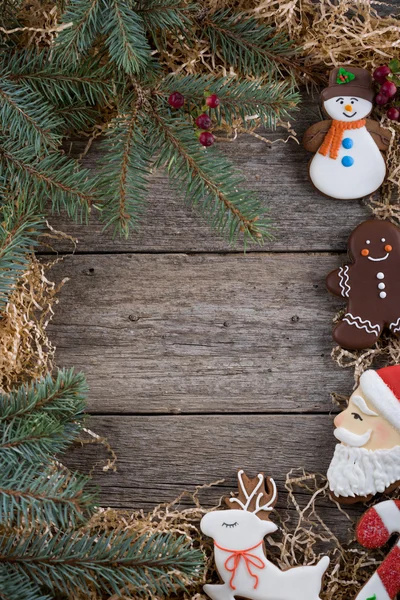 Christmas frame of pine branches. Decoration of painted ginger gingerbread. Gingerbread man, Christmas cane and snowman. Place under the text. Copy space.