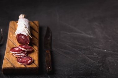 Taze Salam bir vintage yönetim kurulu üzerinde. Vintage çatal çatal ve bıçak bir siyah arka plan kaplı. Kopya alanı.