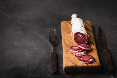 Taze Salam bir vintage yönetim kurulu üzerinde. Vintage çatal çatal ve bıçak bir siyah arka plan kaplı. Kopya alanı.