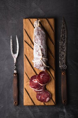 Taze Salam bir vintage yönetim kurulu üzerinde. Vintage çatal çatal ve bıçak bir siyah arka plan kaplı. Kopya alanı.