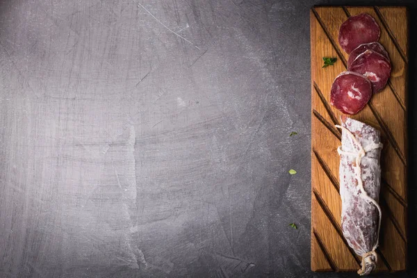 Świeży salami na vintage Board. Vintage sztućce widelec i nóż na czarnym powlekane podłoże. Miejsce. — Zdjęcie stockowe