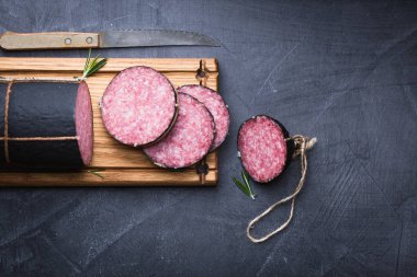 Tatlı sosis, dilimlenmiş otlar, kekik, biberiye ile kara kaplı tahta üzerinde. Vintage bıçak, tahta kesme vintage.