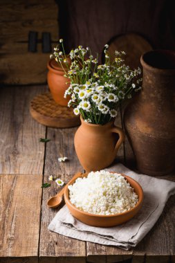 Ahşap arka plan üzerine bir tahta kaşık closeup ile bir kil tencerede peynir. Kil tencere taze süt ile. Uzay kopyalayın. Rustik tarzı.