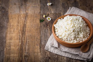 Ahşap arka plan üzerine bir tahta kaşık closeup ile bir kil tencerede peynir. Yukarıdan 90 derecelik bir açıyla vurdu. Kopya alanı.