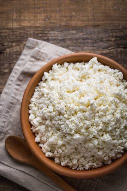 Ahşap arka plan üzerine bir tahta kaşık closeup ile bir kil tencerede peynir. Yukarıdan 90 derecelik bir açıyla vurdu. Kopya alanı.