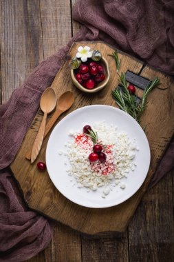 Diyet kahvaltı bir rustik tarzda. Zımba ile şık bir ahşap tahta üzerinde Peynir tabağı. Kızılcık ve biberiye bir kil kase.