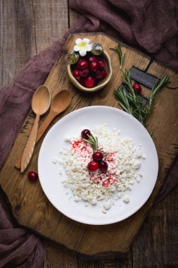 Diyet kahvaltı bir rustik tarzda. Zımba ile şık bir ahşap tahta üzerinde Peynir tabağı. Kızılcık ve biberiye bir kil kase.