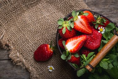 Çilek ahşap bir masa üzerinde. Papatya ve bir sepet ile bir yaz resmi.