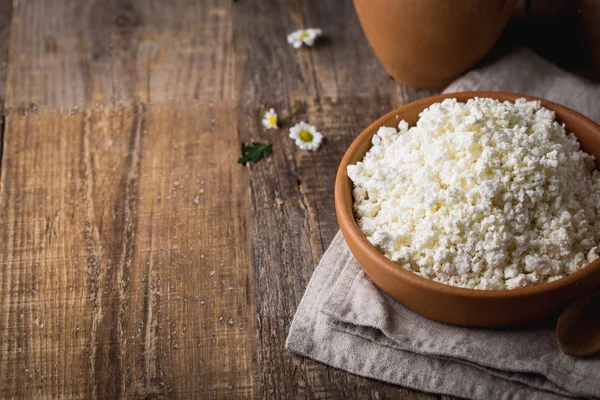 Cottage cheese in a clay pot with a wooden spoon closeup on wooden background. Shot from above at an angle of 90 degrees. Copy space. — Stock Photo, Image