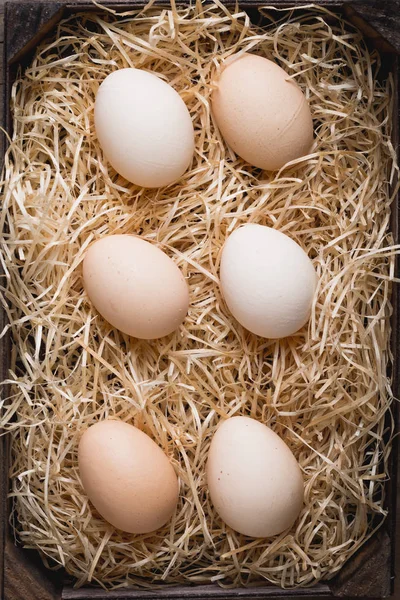 stock image Village eggs laid in a wooden box on the fresh hay. The rustic style. Ingredients for a tasty pie, farm products, diet and nutrition. Copy space.