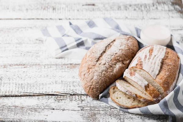 Pâine proaspătă parfumată proaspătă din cuptor. Pâine de pământ pe o masă de lemn, așezată pe un șervețel de pânză . — Fotografie, imagine de stoc