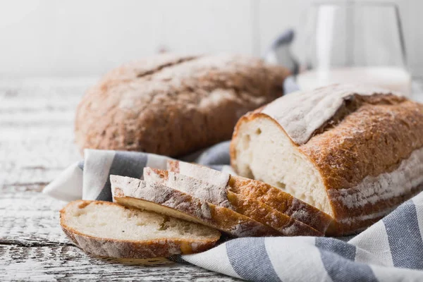 オーブンから新鮮な新鮮な香ばしいパン。布リネン ナプキンに置かれる木製のテーブル、暖炉のパン. — ストック写真