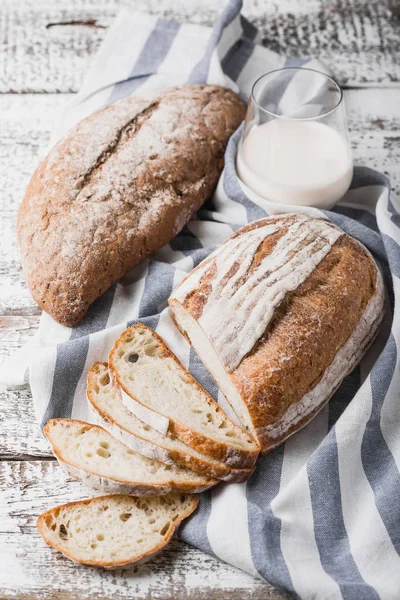 Fresh fragrant bread fresh from the oven. Hearth bread on a wooden table, laid on a cloth linen napkin. — Stock Photo, Image