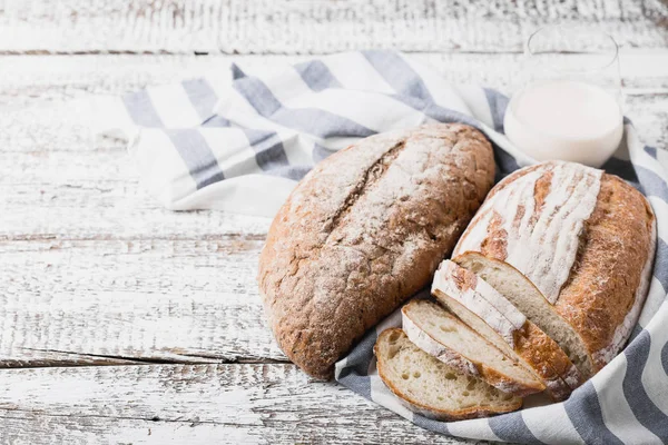 Świeży pachnący chleb prosto z pieca. Palenisko chleb na drewnianym stole, położył na serwetki lniane tkaniny. — Zdjęcie stockowe