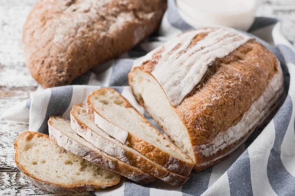 Fresh fragrant bread fresh from the oven. Hearth bread on a wooden table, laid on a cloth linen napkin. — Stock Photo, Image