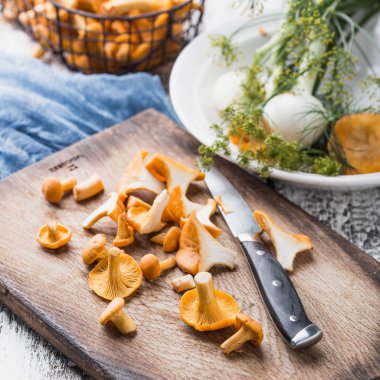 Sonbahar mantar kırmızı, ahşap bir gemide bir bıçakla kesilmiş. Soğan, dereotu masanın üzerinde. Akşam yemeği