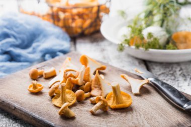 Sonbahar mantar kırmızı, ahşap bir gemide bir bıçakla kesilmiş. Soğan, dereotu masanın üzerinde. Akşam yemeği