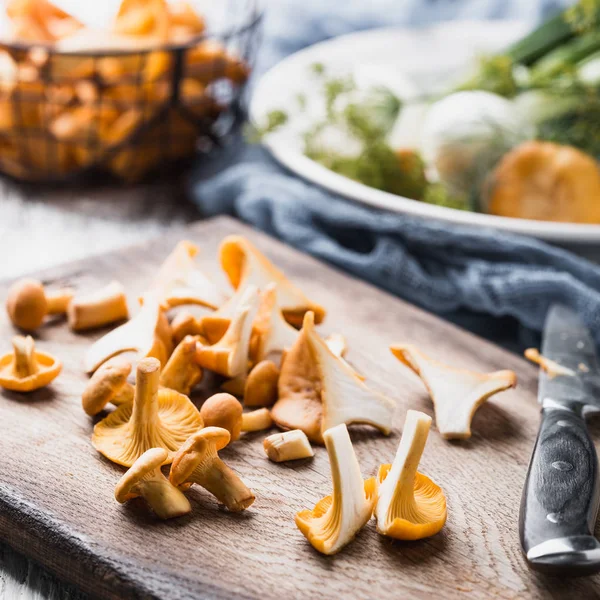 Sonbahar mantar kırmızı, ahşap bir gemide bir bıçakla kesilmiş. Soğan, dereotu masanın üzerinde. Akşam yemeği