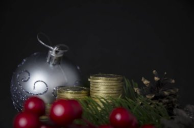 Siyah arka planda Noel oyuncakları ve bozuk paralar. Kazakistan tentesi ve Noel süsü. Sikkeler kazastan tenge 2020. Kazak parası ve yeni yıl oyuncakları, koniler, böğürtlenler.