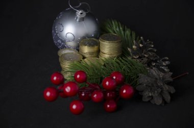 Siyah arka planda Noel oyuncakları ve bozuk paralar. Kazakistan tentesi ve Noel süsü. Sikkeler kazastan tenge 2020. Kazak parası ve yeni yıl oyuncakları, koniler, böğürtlenler.