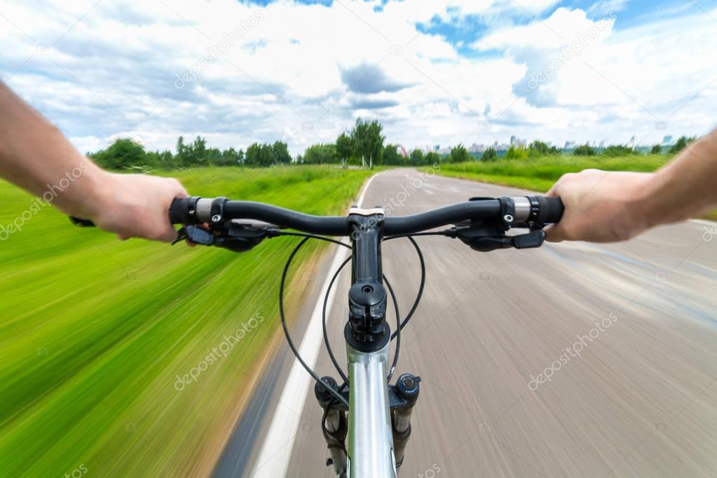 Rider driving bicycle on an asphalt road.