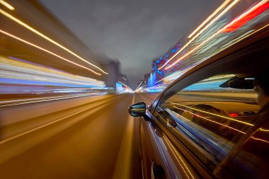 Side of Car 'ın bir gece şehrinde giderken görüntüsü, Blured Yolu' nda yüksek hızda arabalı ışıklar. Modern bir şehrin hızlı ritmini kavra.
