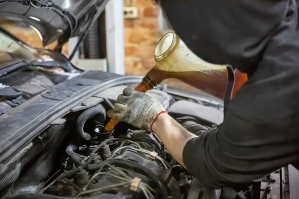 auto mechanic technician replacing and pouring motor oil