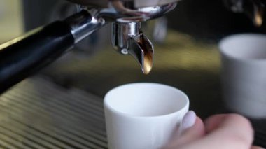 Full process of making coffee on professional coffee machine. Barista preparing double espresso, pouring it in cup.