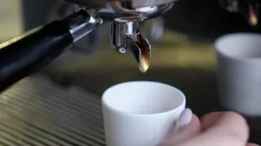 Full process of making coffee on professional coffee machine. Barista preparing double espresso, pouring it in cup.