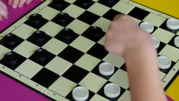 Děti hrají dámu na barevném stole. Chlapec a dívka soutěžit v deskových hrách. — Stock video