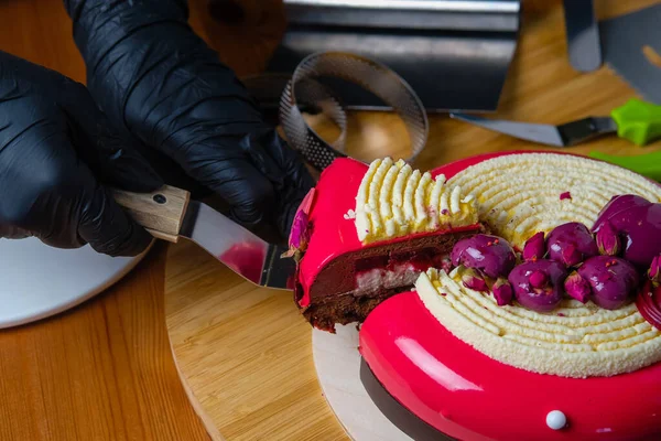Pasta şefi modaya uygun bir kremalı pasta kesiyor. Modern tatlının hazırlığı..