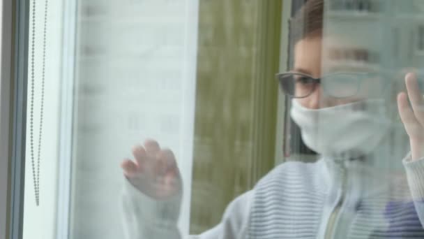 医者のマスクと眼鏡の少年が窓の外を見ている コロナウイルス Covid 19における自己分離 — ストック動画