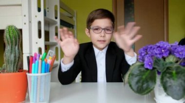 Gözlüklü küçük çocuk kameraya konuşuyor. Çocuk bilimsel bir video günlüğü tutuyor.