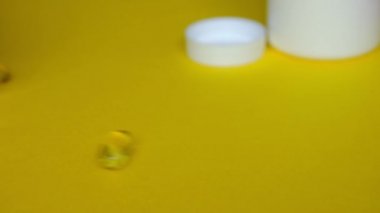 Altın omega 3 balık yağı kapsülleri sarı zemine düşer..