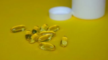 Aile Omega 3 'ü seve seve kabul eder. Sarı arka planda balık yağı kapsülleri.