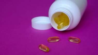 Çocuklar Omega 3 almaktan mutlu olurlar. Mor arka planda altın balık yağı kapsülleri.