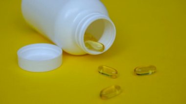 Çocuk seve seve Omega 3 alır. Sarı arka planda balık yağı kapsülleri.