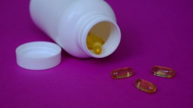 Çocuklar Omega 3 almaktan mutlu olurlar. Mor arka planda altın balık yağı kapsülleri.