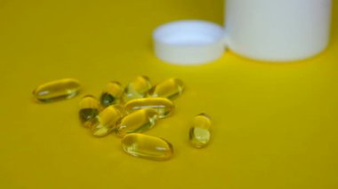 Omega 3 'ü alacak adam. Sarı arka planda balık yağı kapsülleri.