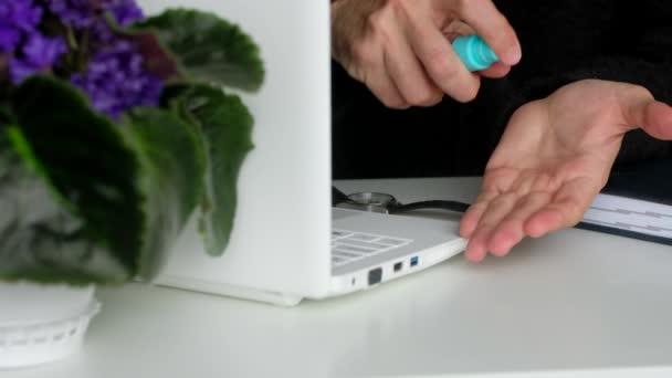 Sanitizer. Geschäftsmann behandelt seine Hände vor der Arbeit am Laptop mit Antiseptika. Antibakterieller Wirkstoff. — Stockvideo
