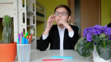 Gözlüklü küçük çocuk kameraya konuşuyor. Çocuk bilimsel video günlüğü tutuyor.