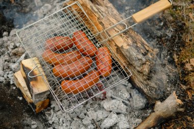 Erkek ve kadın domuz sucuğu veya sosis pişiriyor..