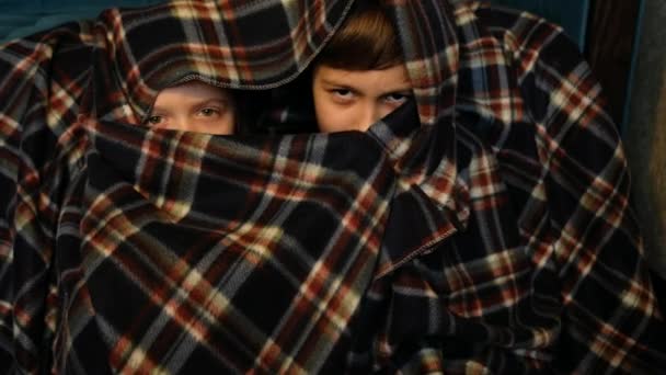 Bambini che guardano la TV di notte. Giovane ragazzo e ragazza si nascondono in una coperta dallo spavento . — Video Stock